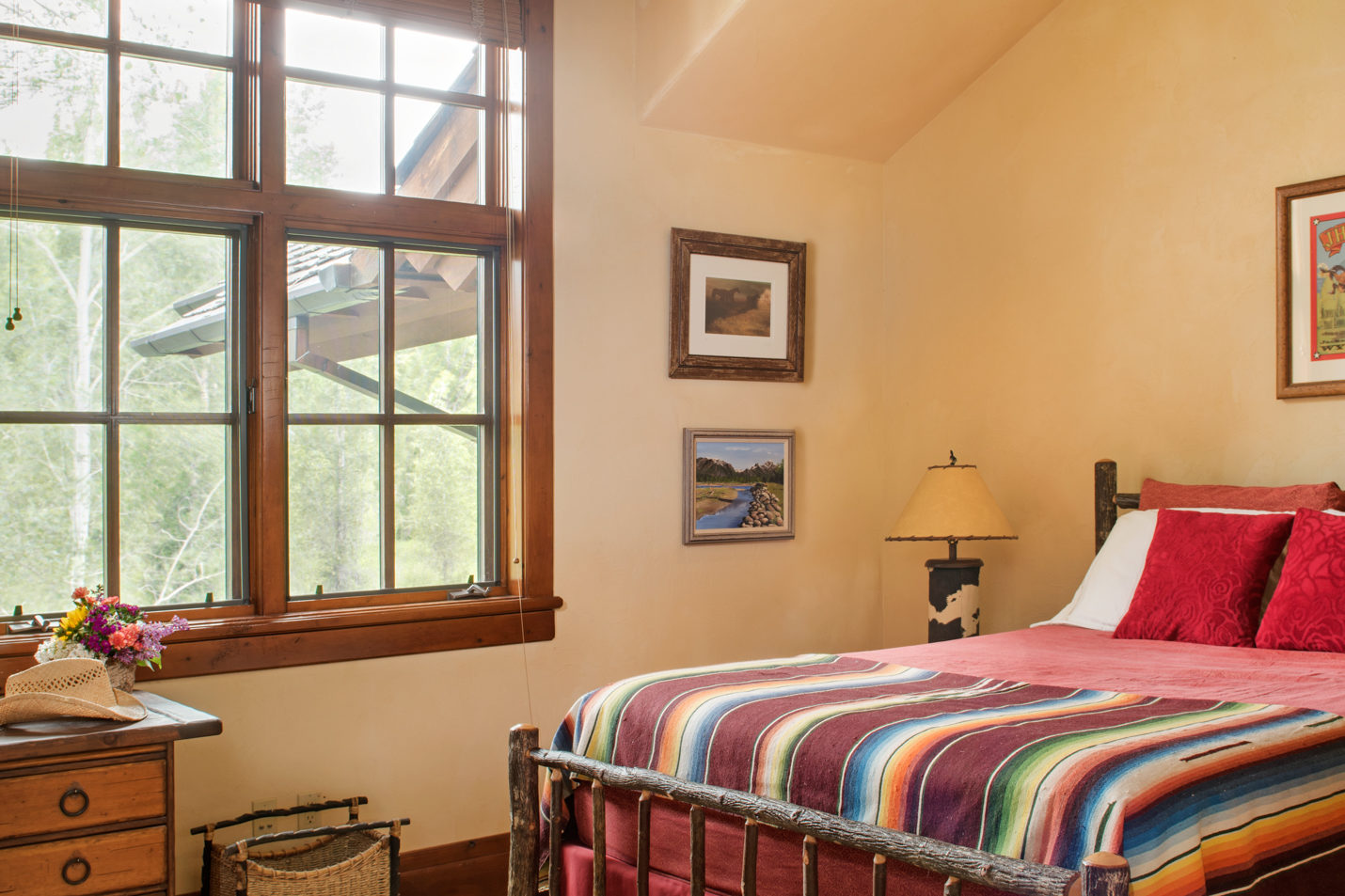 A bedroom with a queen sized bed and western artwork