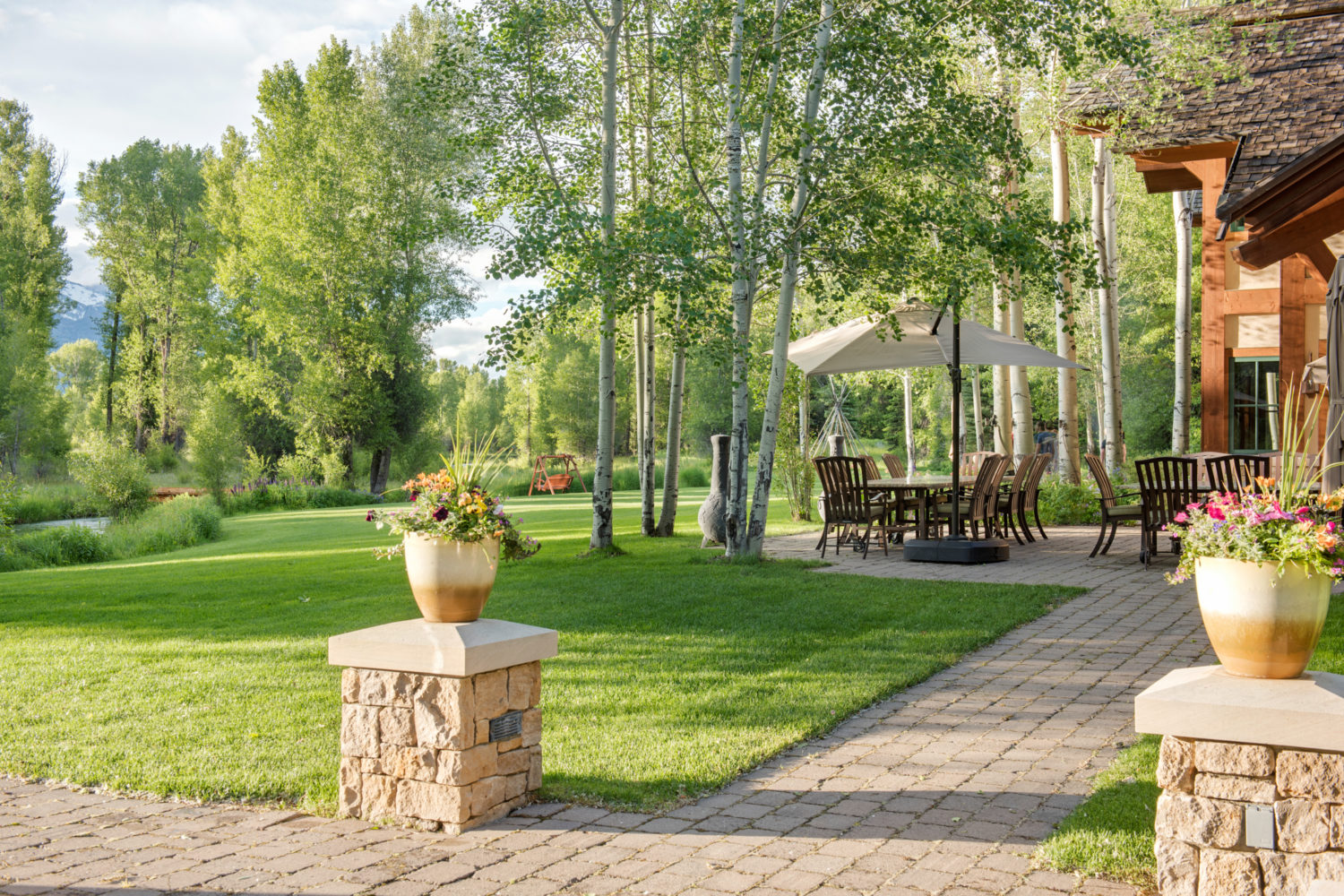 A paved path with flowers and a lawn and outdoor dining area
