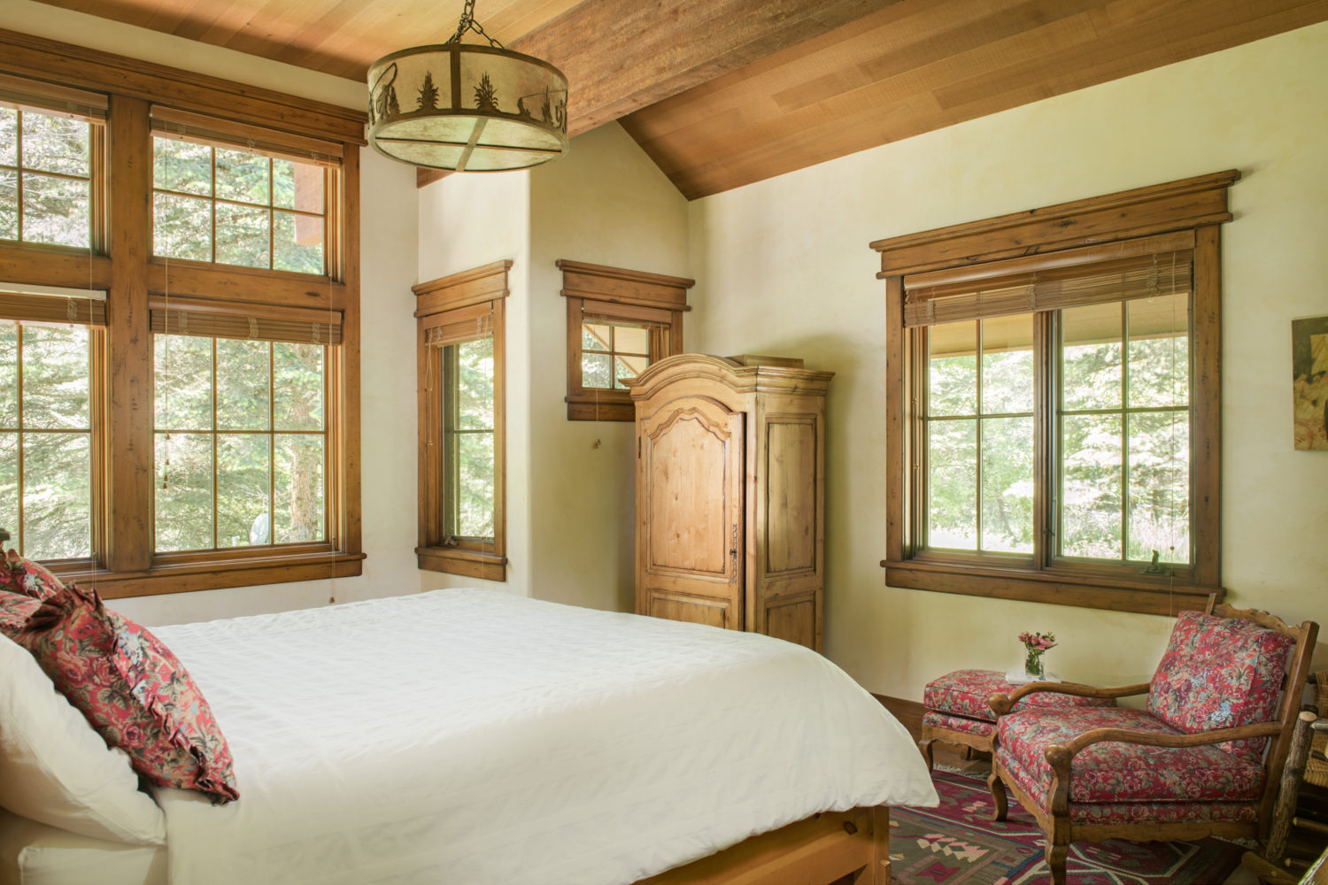 A bedroom with a king sized bed and windows with natural light