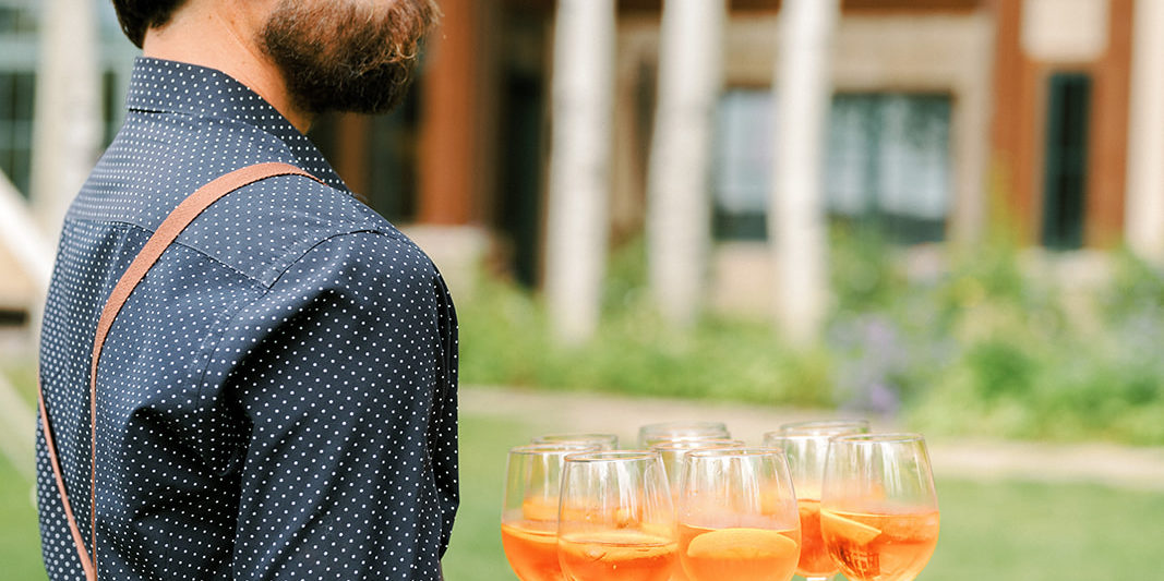 A waiter carries a tray of aperol spritzes