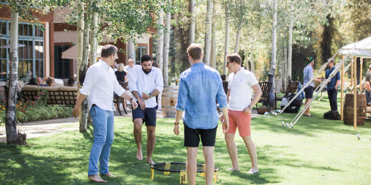 A group of men play a game of Spikeball on the lawn