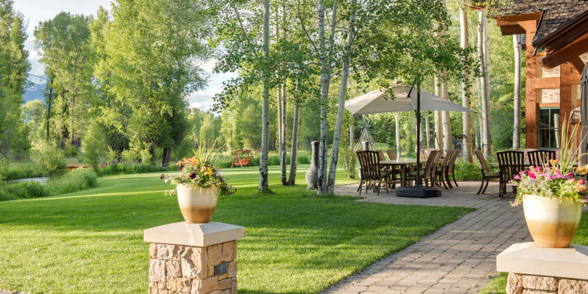A manicured lawn with flowers and trees and an outdoor dining area