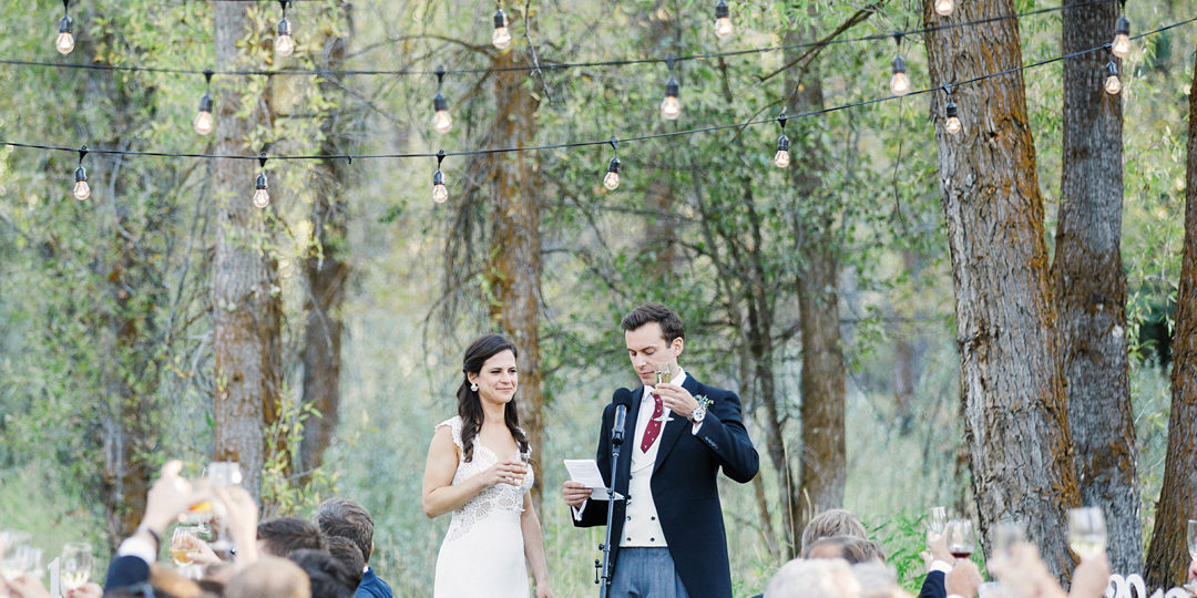 A bride and groom raise a toast to their guests during their wedding dinner