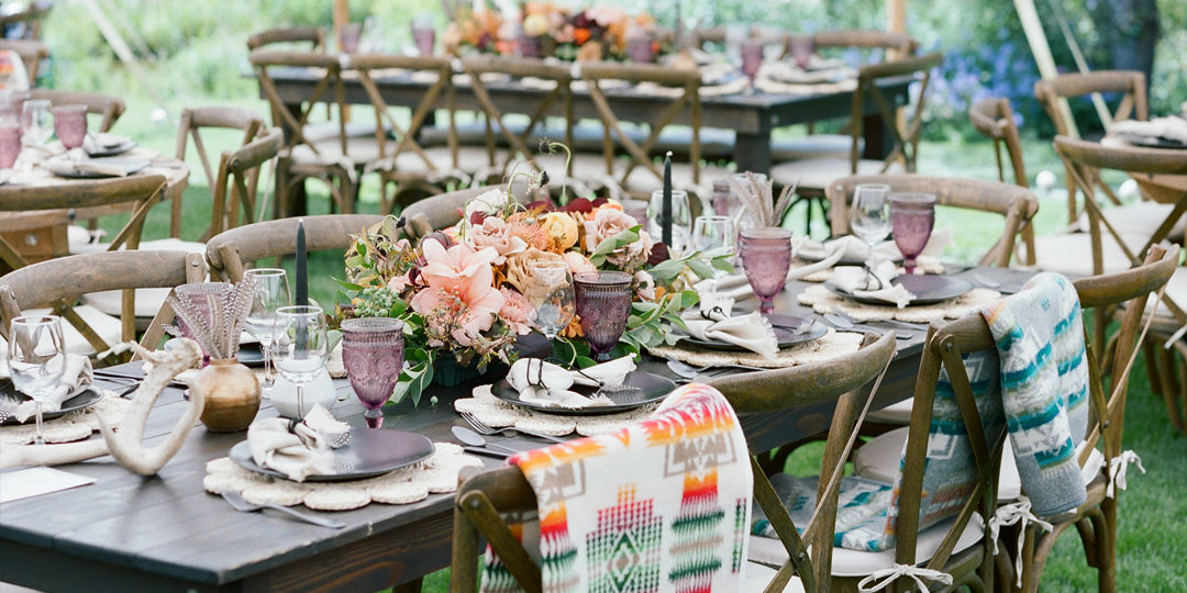A boho style dining table set up with flowers and pendleton blankets